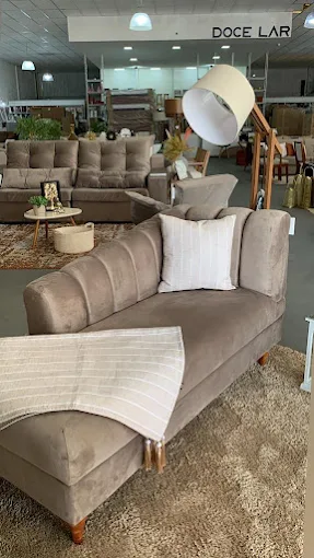 Sofá bege com chaise, manta listrada e luminária de piso